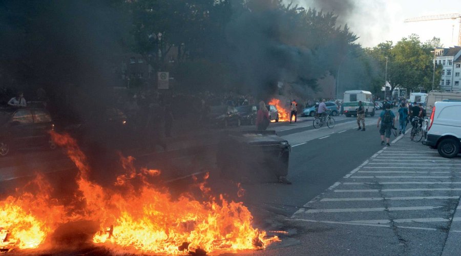 Feuer und umgekippte Müllcontainer auf einer Straße.