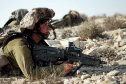 VISIER Special 83 Moderne Sturmgewehre Soldatin liegt mit Tavor C-TAR 21 in steiniger Wüstenlandschaft.