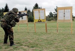 VISIER Special 83 Moderne Sturmgewehre. Soldat zielt mit dem G36 auf T-Scheiben, die an Holztafeln befestigt auf einer Wiese stehen.