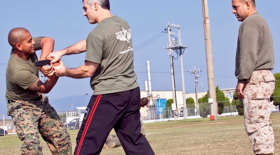 VISIER Special 85 "Selbstschutz & Sicherheit" Ein Soldat wehrt sich gegen einen anderen Soldaten mit Trainingsmesser, ein dritter Soldat beobachtet die Szene.