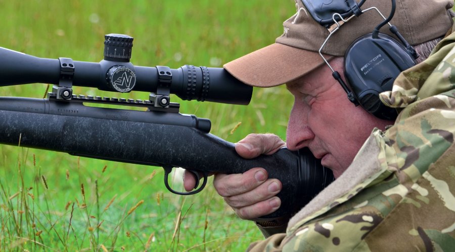 Andrew Venables im Profil auf der Wiese mit Long-Range-Gewehr im Anschlag.