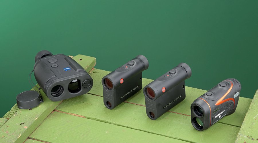 4 Laser-Entfernungsmesser auf hellgrüner Holzkiste vor dunkelgrünem Hintergrund.