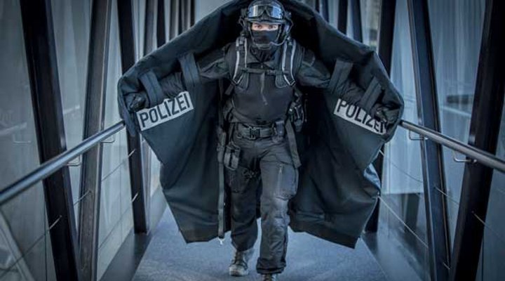 VISIER Special 87 Polizist mit ausgebreiteter Geiselschutzdecke läuft einen Gang hinunter.