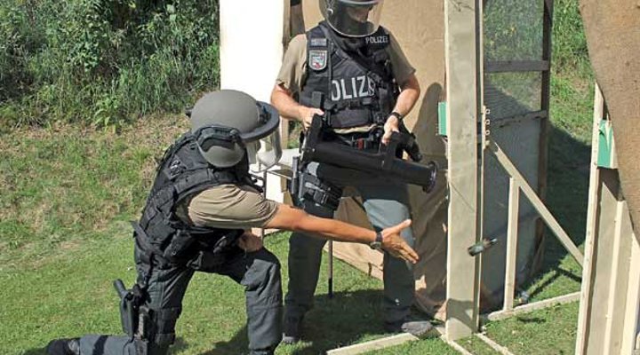 VISIER Special 87 Ein Polizist öffnet mit einer Ramme eine Tür und sein Kollege wirft ein Flashbang hindurch.