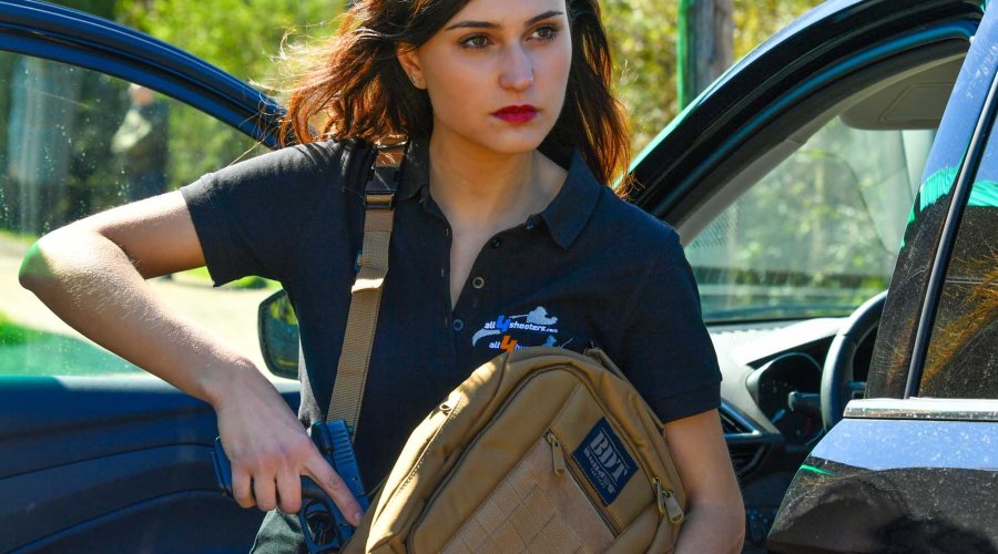 Girl pulling out the gun from the Bulldog Carry Sling Pack Small Tan