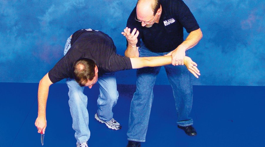 Two men demonstrate the defense to ward off a knife attack with their bare hands. 