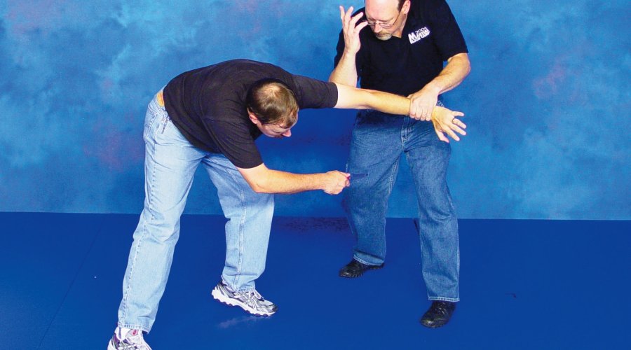 Two men demonstrate the defense to ward off a knife attack with their bare hands. 