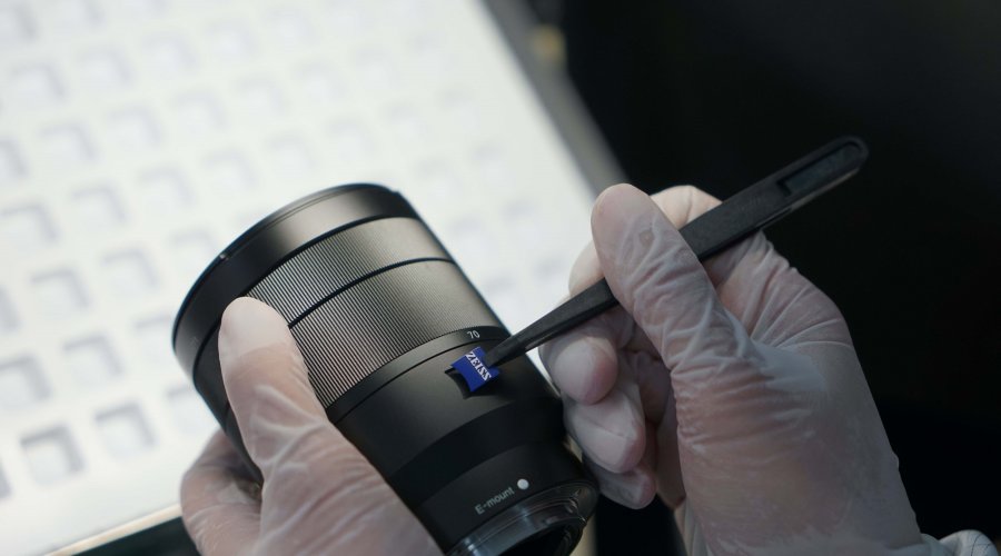 Worker applying the Zeiss logo on a camera objective