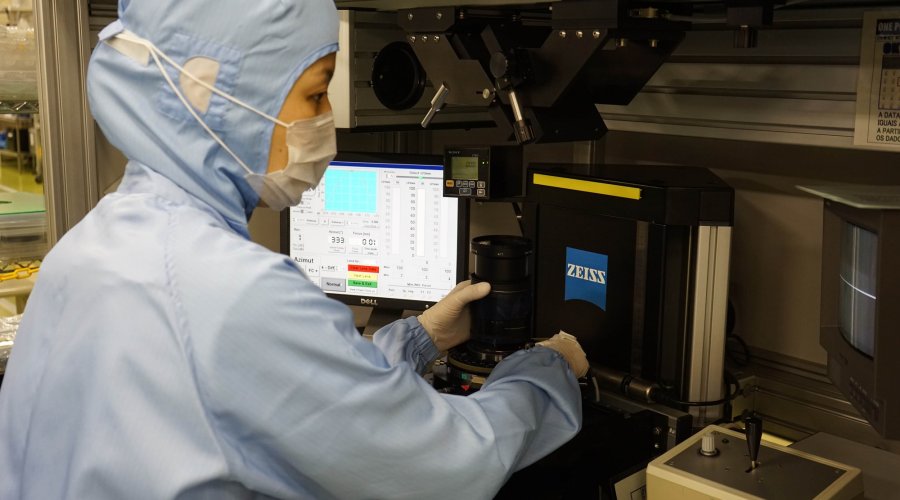 A Zeiss worker operating an optics quality control machinery