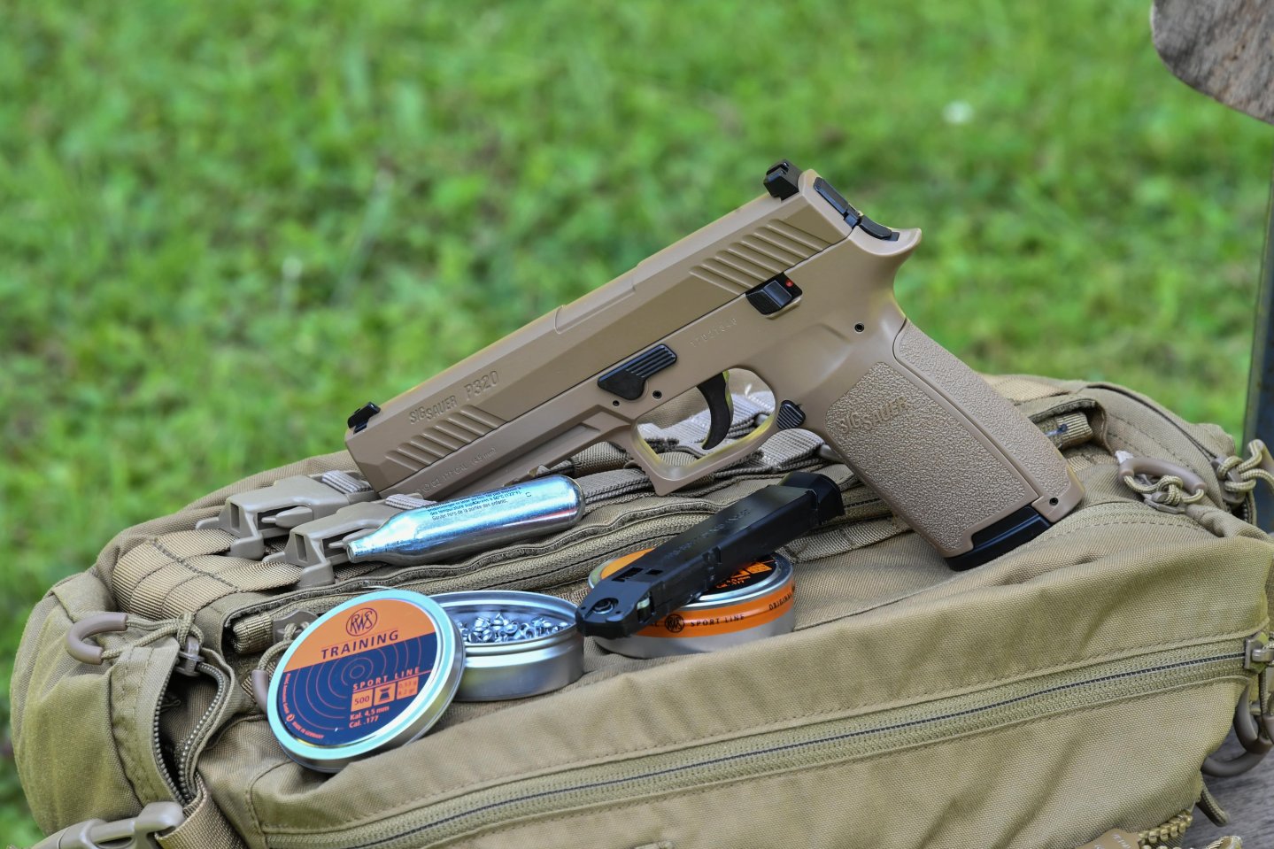 SIG Sauer P320 ASP at GSG: the air pressure gun on the shooting range The SIG Sauer P320 ASP air gun lies next to a rotary magazine, pellets and a CO2 cartridge