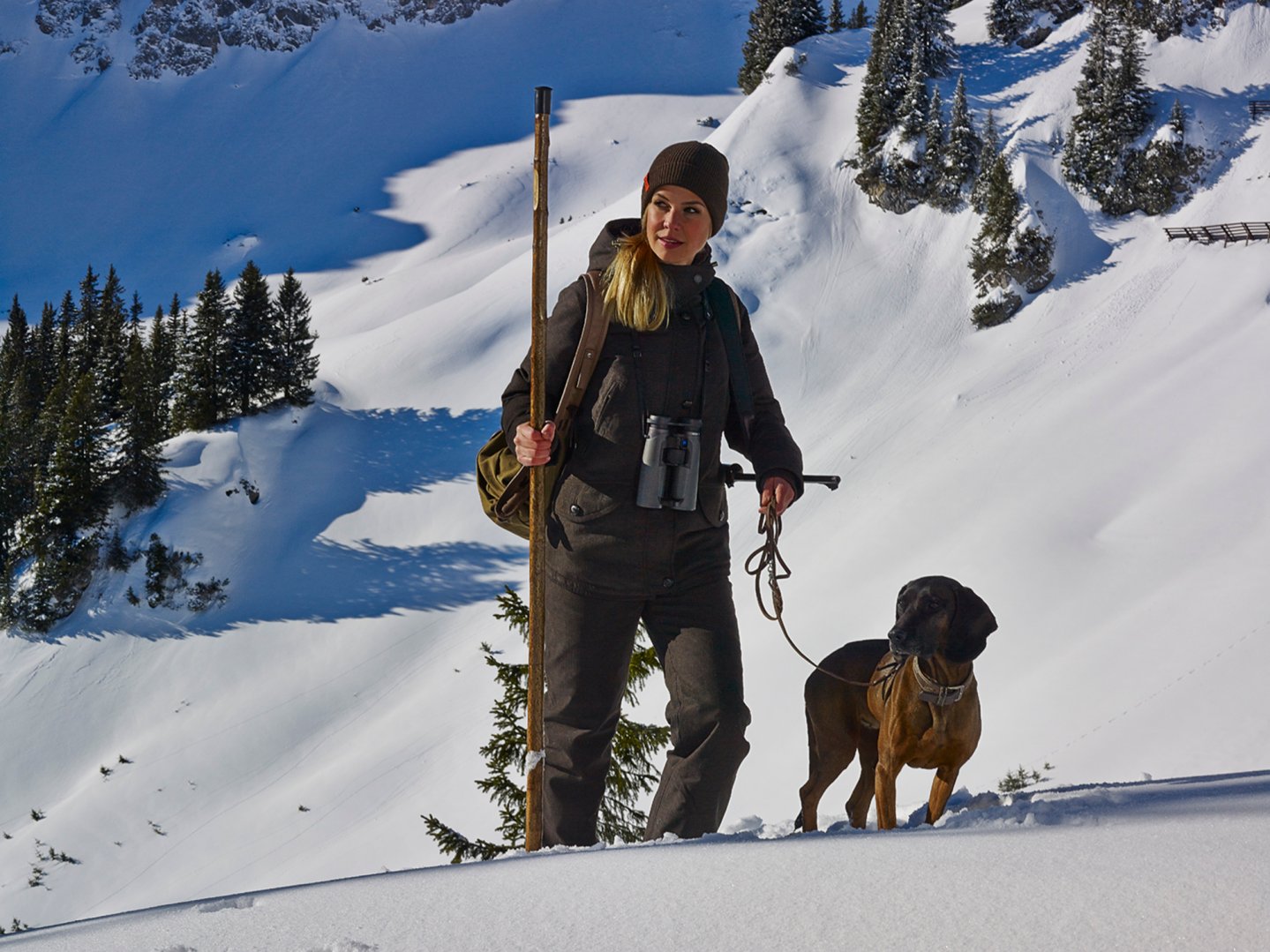 Una cacciatrice con un cane nella neve