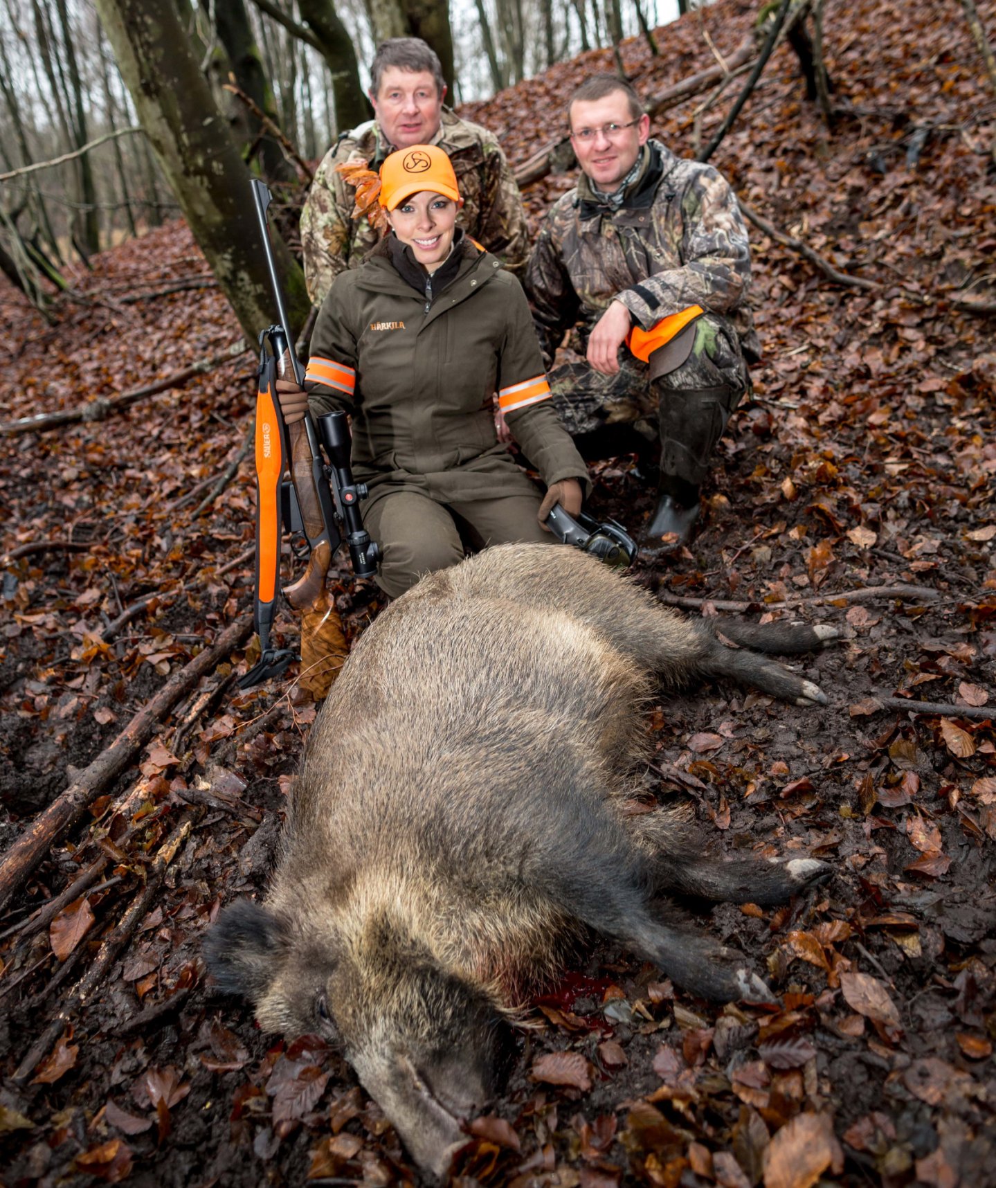 Selena Barr e due cacciatori con cinghiale in primo piano