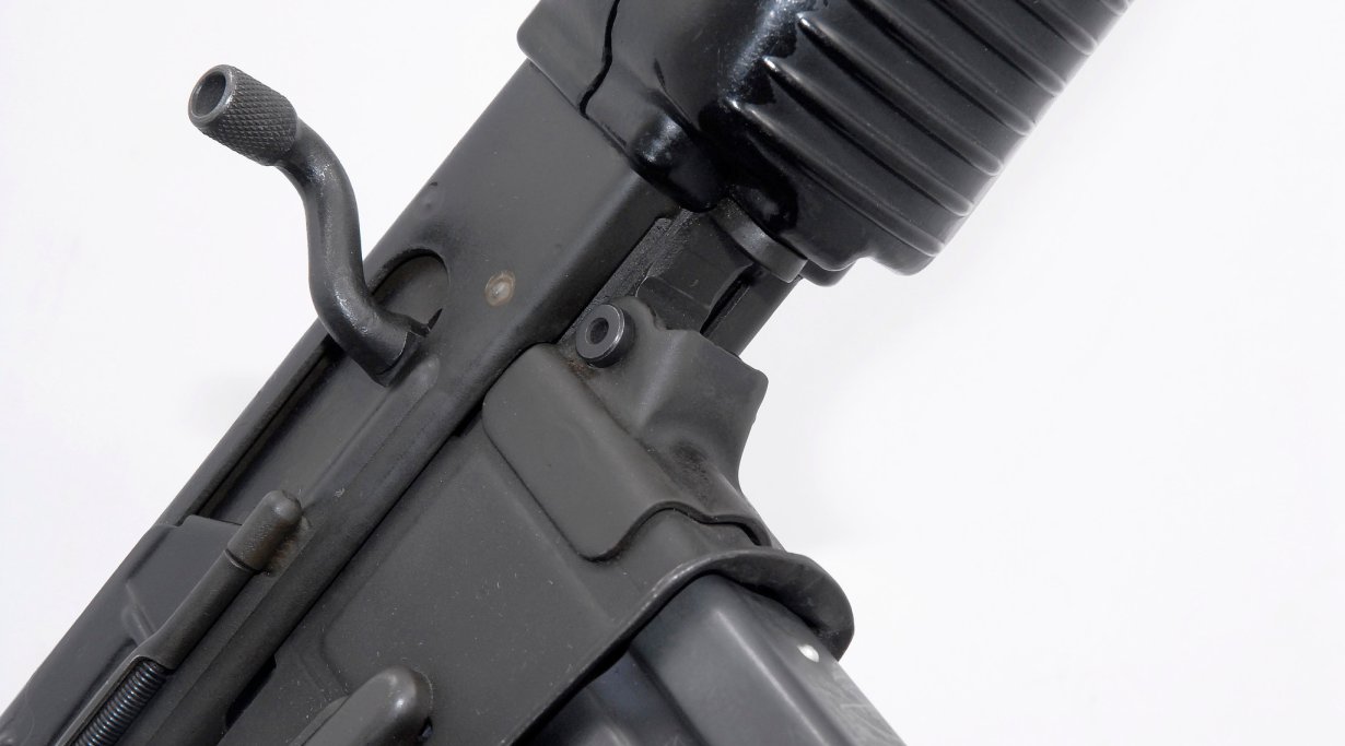 La sede del perno anteriore è in lamiera stampata. Il labbro metallico che protrude inferiormente serve da punto d'arresto per il basculamento dell'upper receiver. Il vano caricatore è scampanato per agevolare l'inserimento.