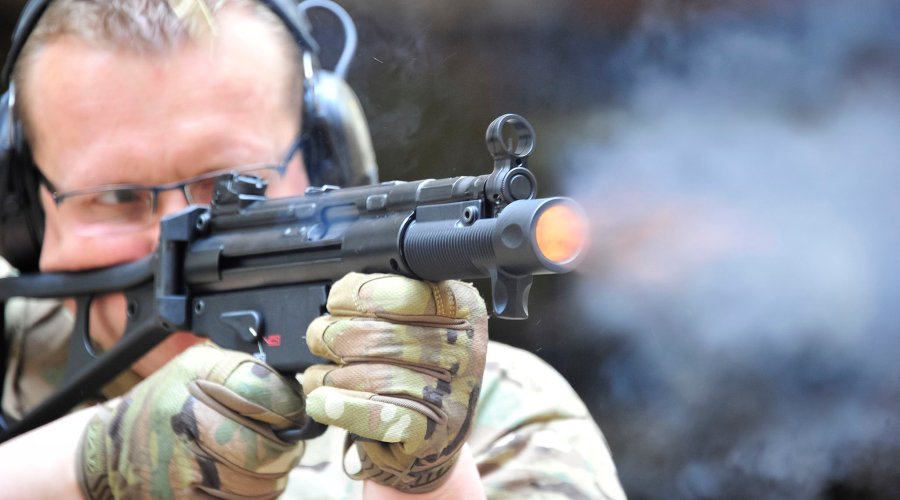 Tiratore con pistola semi-automatica Heckler & Koch SP5K all'imbracciata, con vampa di bocca