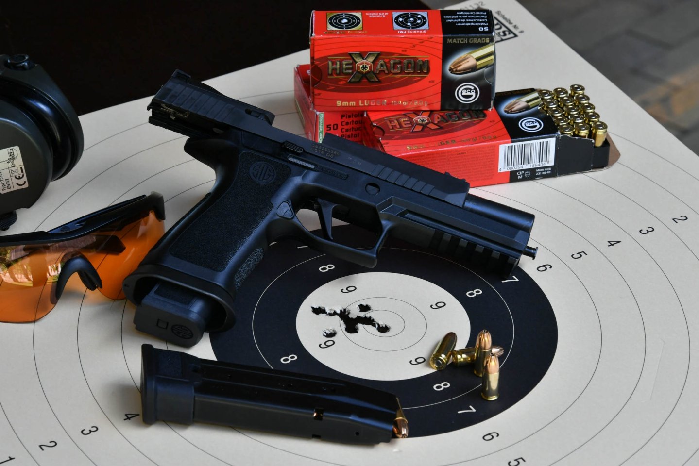 Test: SIG Sauer P320 X-Five – la nave ammiraglia Pistola SIG Sauer P320 X-Five in 9 mm Luger con il suo caricatore, occhiali da tiro, cuffie da tiro e cartucce GECO Hexagon su bersaglio.