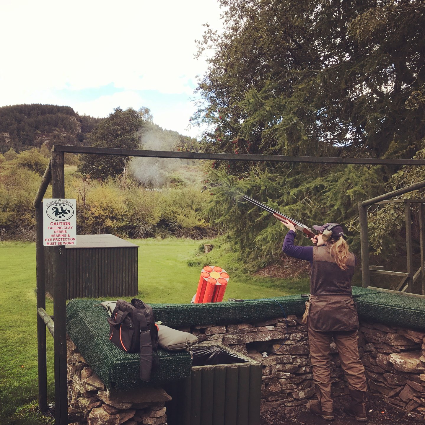 Женщина-стрелок стреляет по тарелочкам 